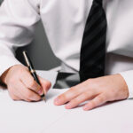 A professional man in a white shirt and tie is focused on writing, representing trusted notarization expertise.