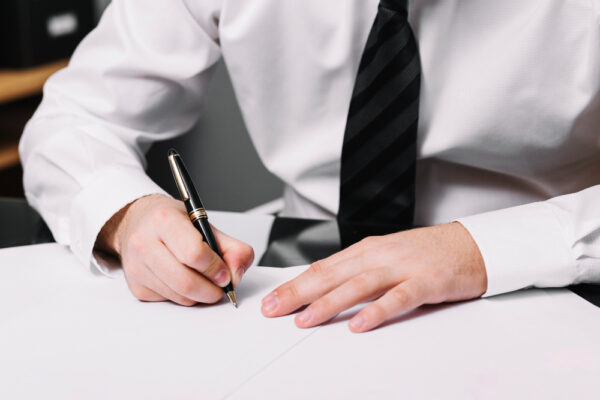 A professional man in a white shirt and tie is focused on writing, representing trusted notarization expertise.