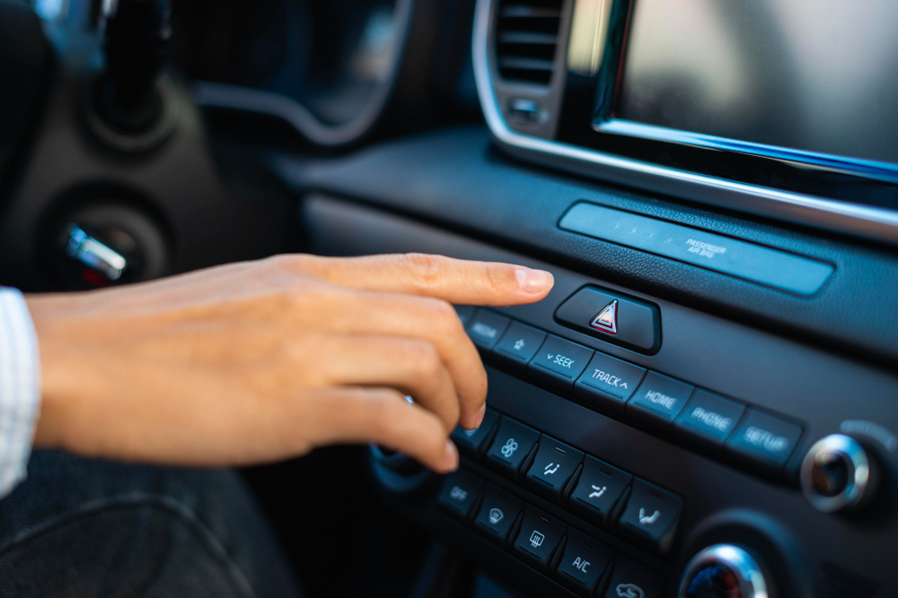 A person pressing a button on a car's dashboard, focusing on car radios and organized stowing solutions.